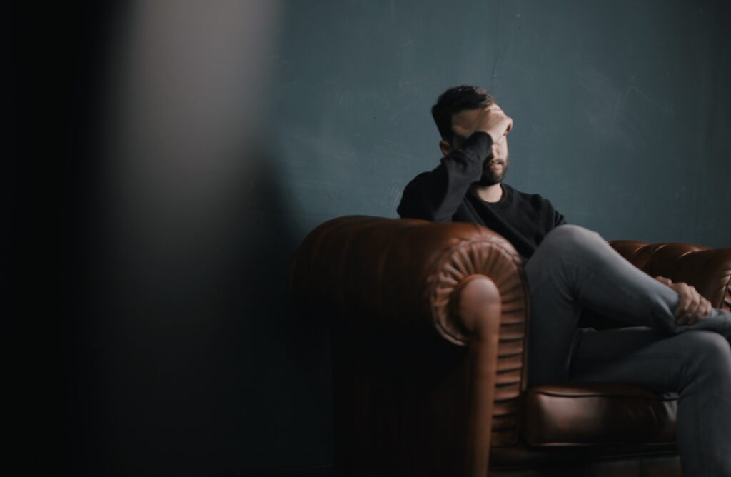 A worried man sitting in a couch during therapy