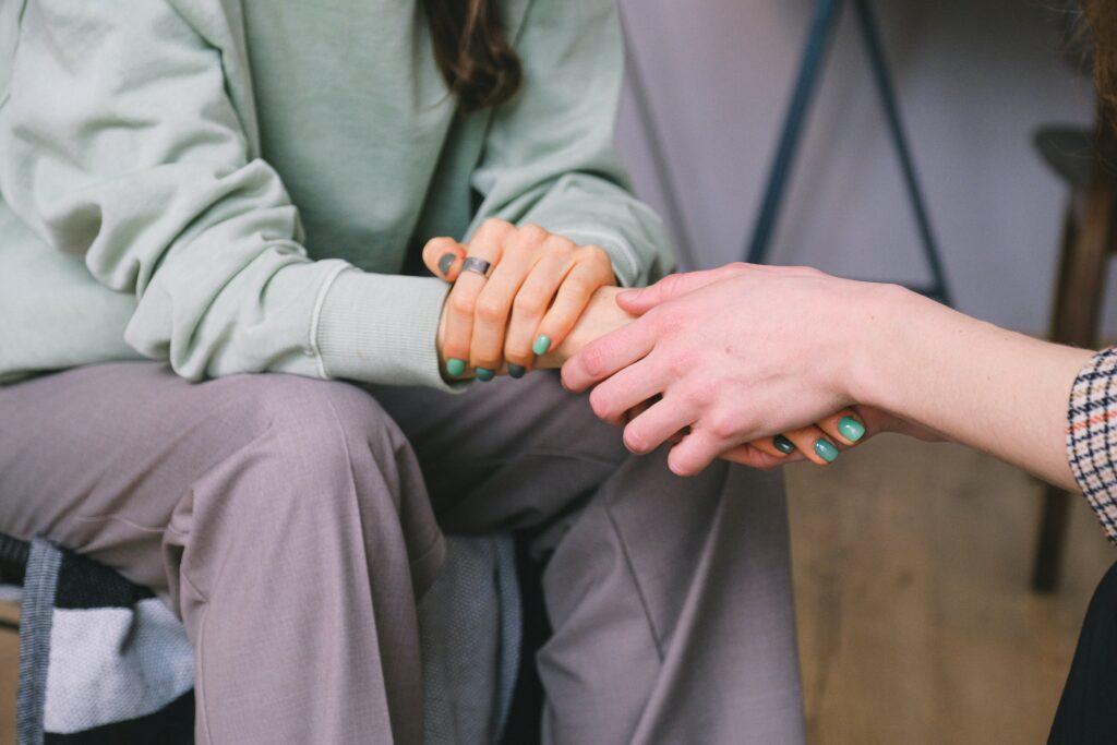A patient and a counselor hold hands during a session.