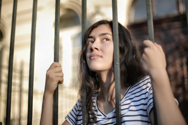 A lady staring out of iron bars